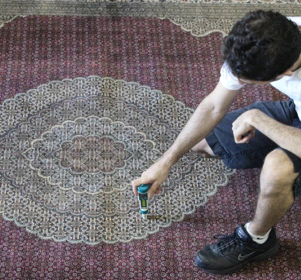 Close-up of a pH meter and dye-stability test on a rug corner before washing